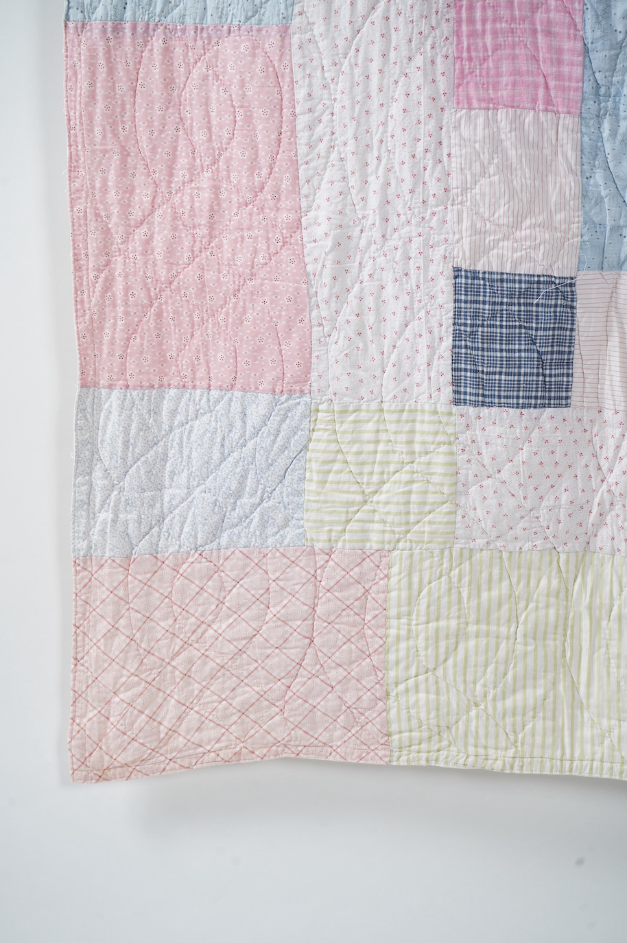 A 1900-1910 English, possibly north country hand quilted bedcover. Designed with a large central medallion, hand quilted using mostly pastel patterned and plain cottons and feature red and black cottons as highlights, ba